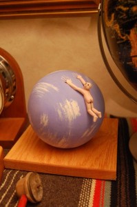 Sphere of Falling - a man hanging on to the top of a globe