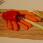 Carrots, red-bell pepper, celery on a wooden cutting board