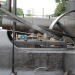 Picture of the piston slide, flywheel, belts, and oil cups of a large stationary steam engine.