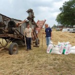 Picture of antique threshing machine, crew, pile of straw, sacks of grain