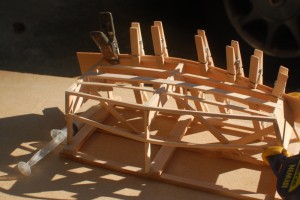 The side glued and clamped to the chine and rail on the building frame.  The clamps are small clothes pins.